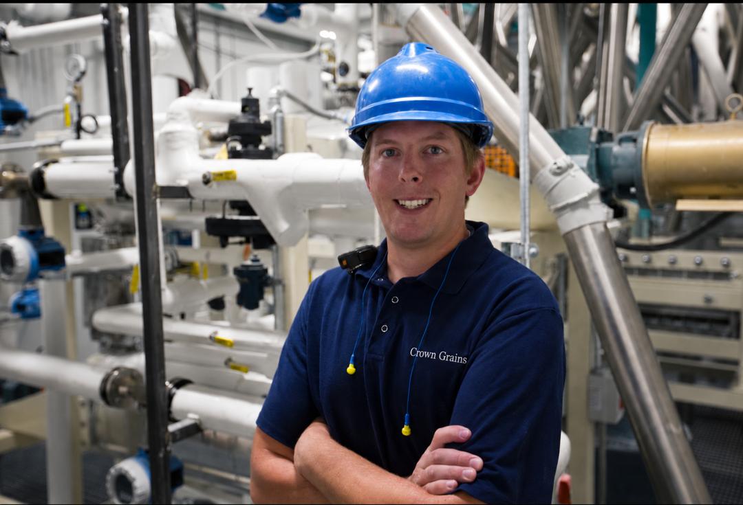 Employee stands against milling equipment